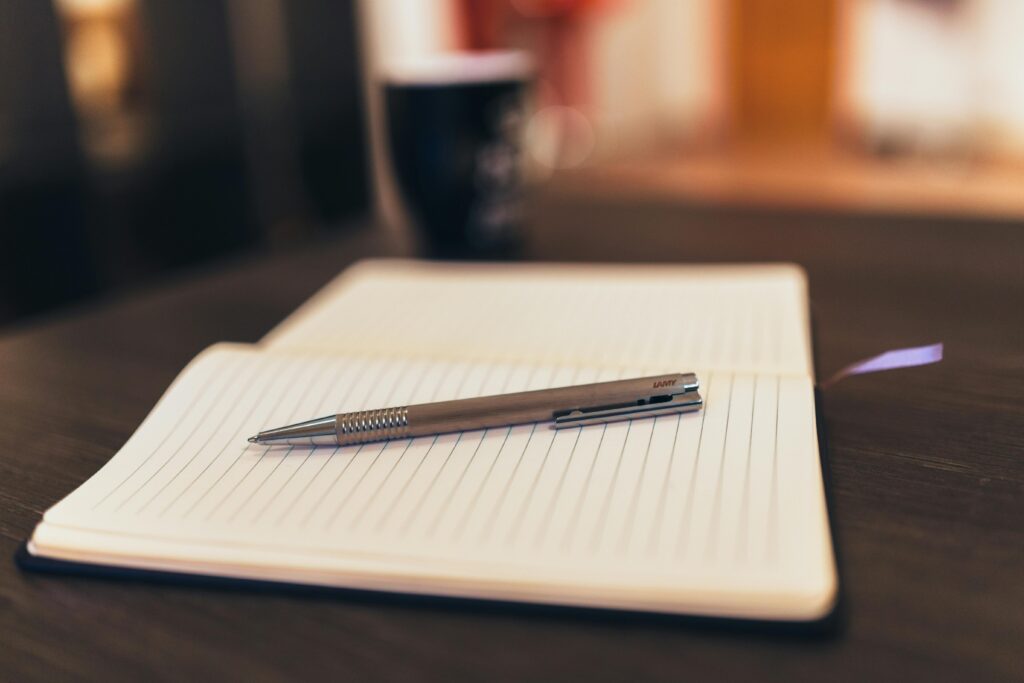 A warm wooden table holding a notebook, fountain pen, and coffee mug, inviting a moment of journaling and quiet reflection.