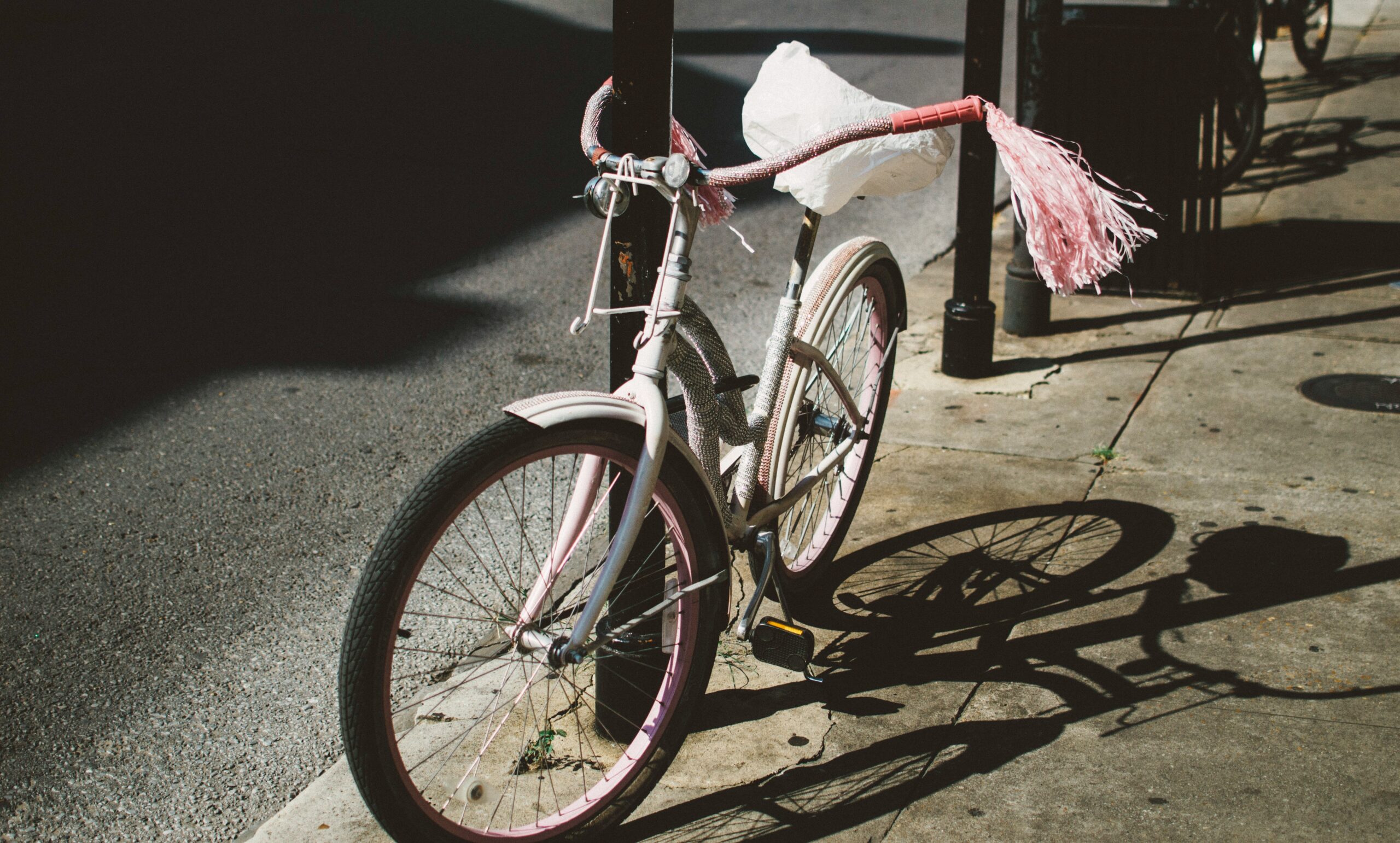 Pink and white child’s bicycle with handlebar streamers parked on a city sidewalk in sunlight as a reminder of how God speaks through your childhood