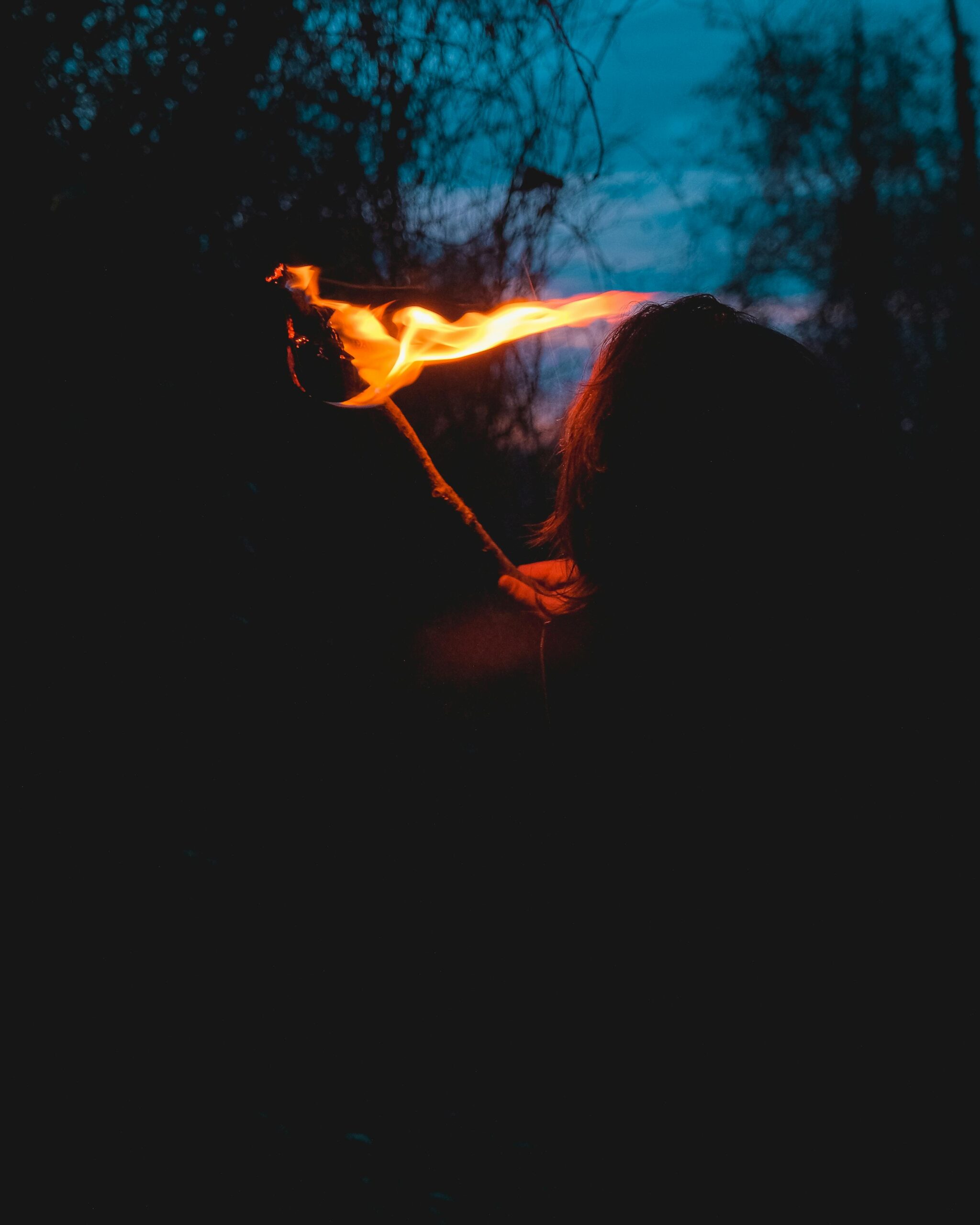 Woman holding a torch in the dark forest symbolizing trusting God instead of self-reliance.